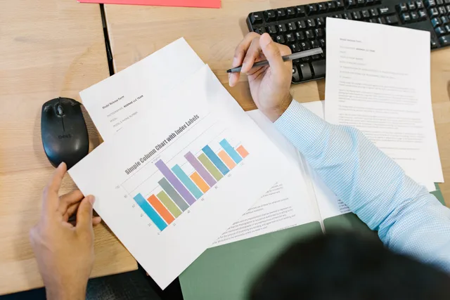 A business analyst reviews a colorful bar chart and documents at a desk, indicating data analysis. When to build a local SEO reporting dashboard instead of a report pack
