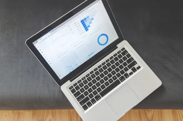 Overhead view of a laptop showing data visualizations and charts on its screen. Before you buy local SEO tools, define the question they must answer